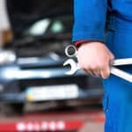 Car mechanic holding spanners