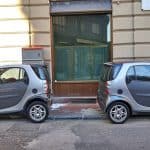 Two Very Small Identical Gray Cars Are Parked In The Same Parkin