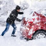 Man Pushing A Car Stuck In The Snow After Heavy Snowfall