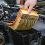 Replacing A Clogged Orange Car Air Filter During General Vehicle