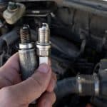 Man Holding old and new car spark plugs