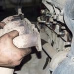 A Mechanic Removes The Exhaust Manifold From An Automobile Inter