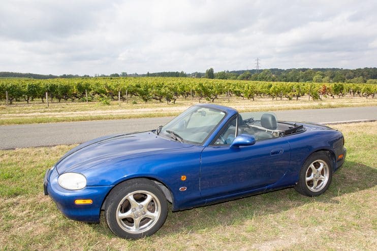 Blue Mazda MX-5 side view.